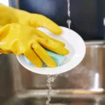 washing dishes with a pair of rubber dishwashing gloves