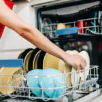 a lady arranging dishes in a dishwasher