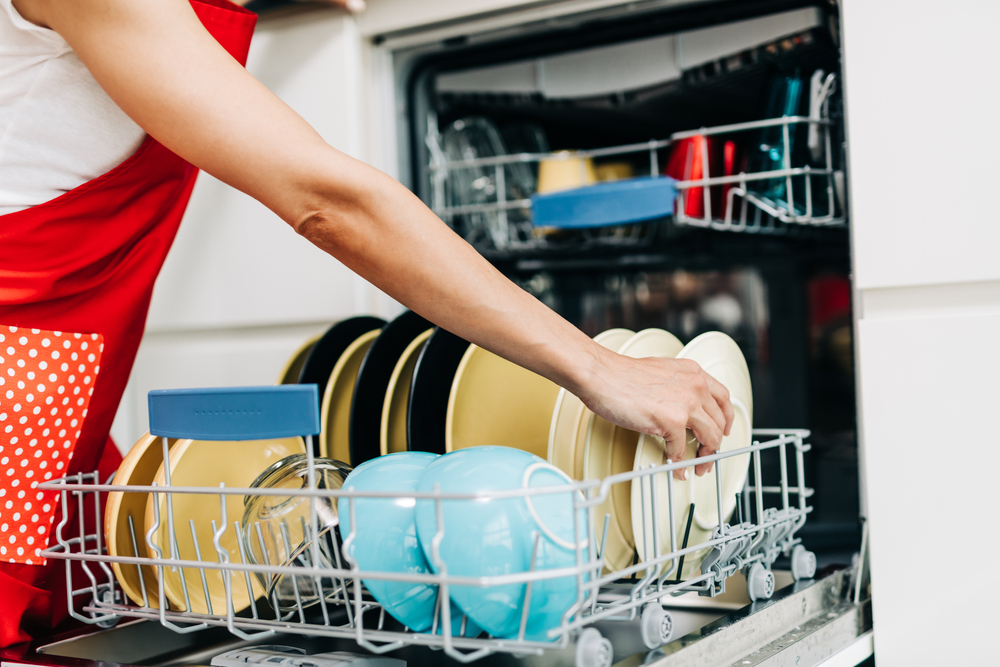 a lady arranging dishes in a dishwasher
