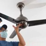 a man cleaning a ceiling fan