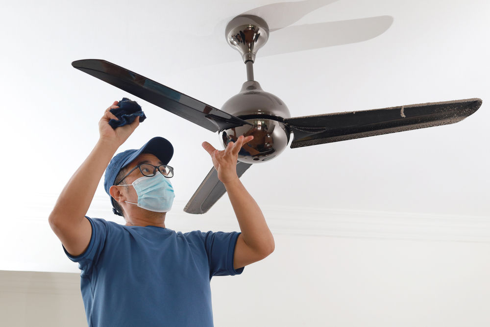 a man cleaning a ceiling fan