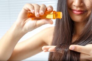 a girl applying oil to her hairs