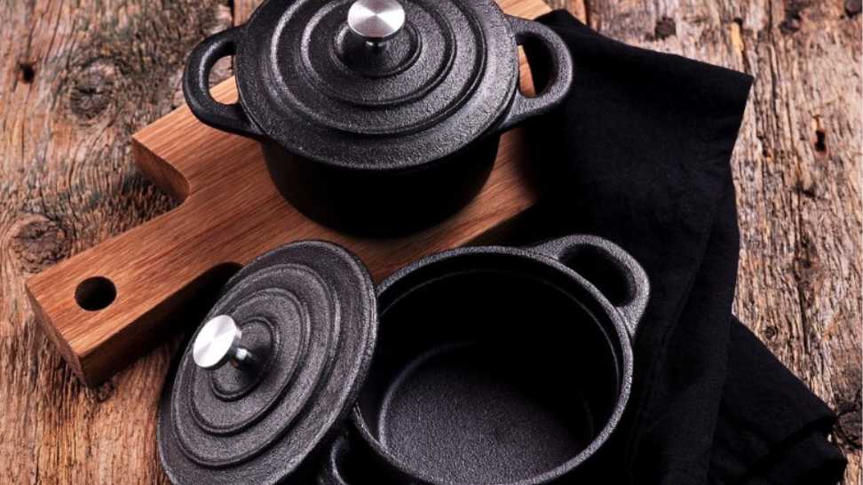 small cast iron pan and cutting board on wooden background