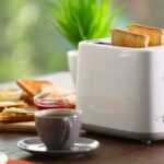 a bread toaster with slices of bread and a cup of tea