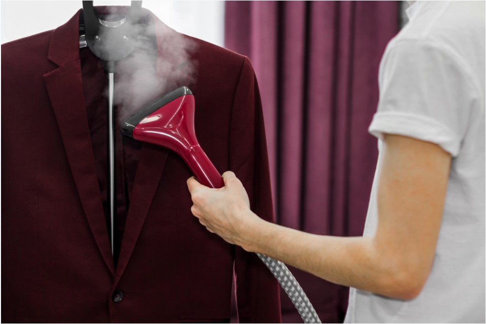 a woman ironing a blazer with a garment cleaner