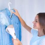 a woman steaming a shirt with a garment steamer
