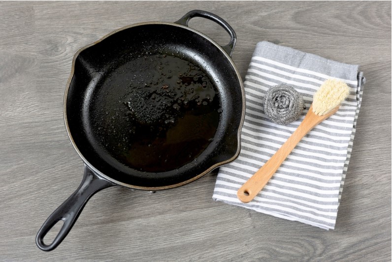 a seasoned cast iron pan with a brush and paper towel