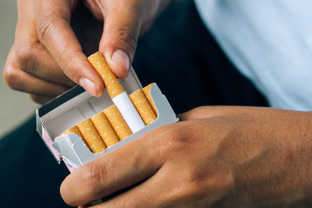 a man holding a packet of cigarette