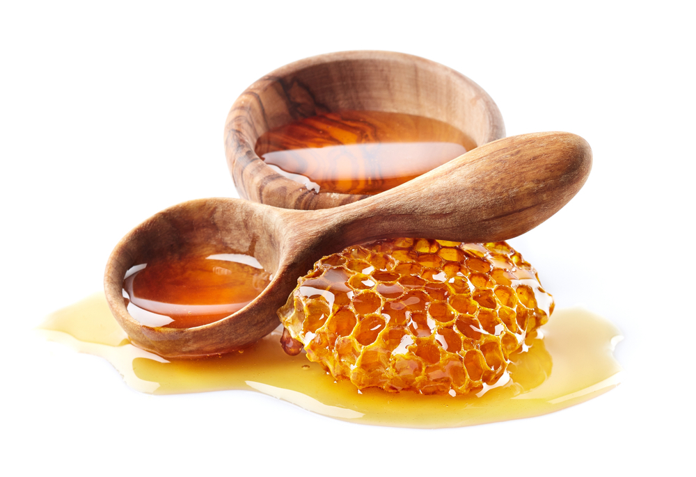 a wooden spoon filled with honey near honeycomb