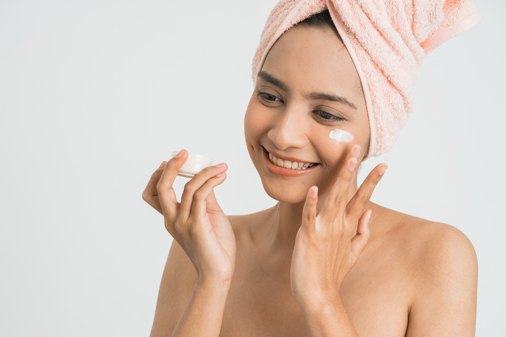 a young woman applying moisturizer