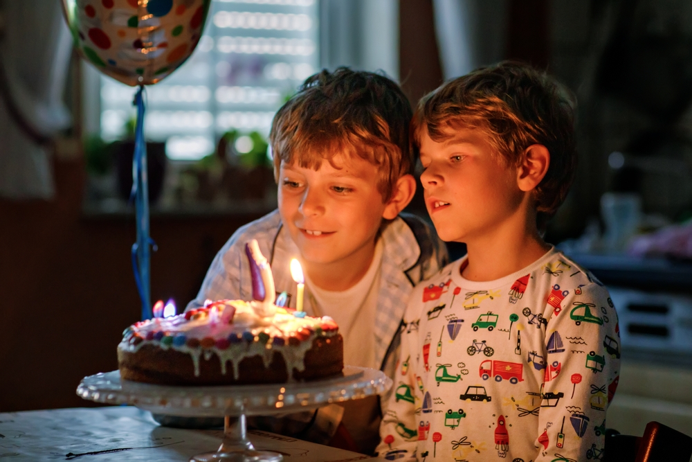 Two brothers celebrating birthday, blowing candles.