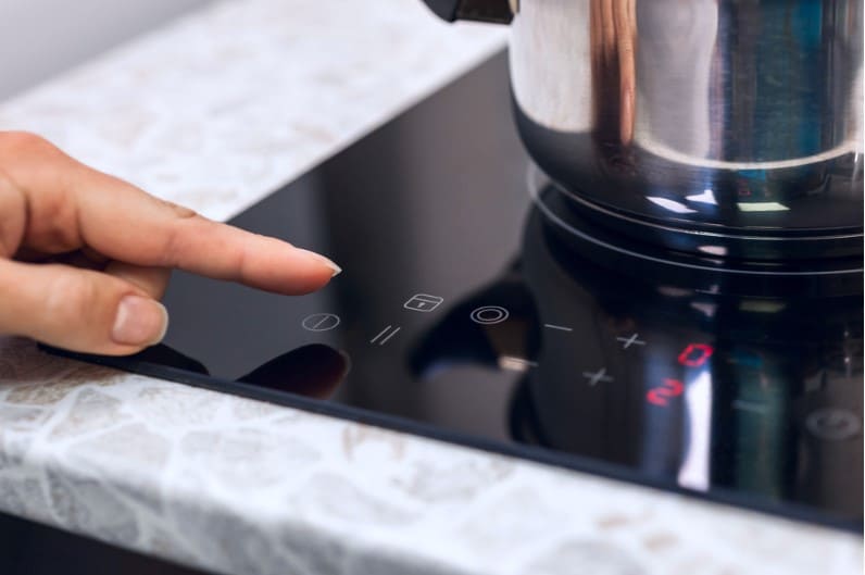 woman hand turning on induction stove