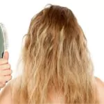a girl with frizzy hair holding a brush