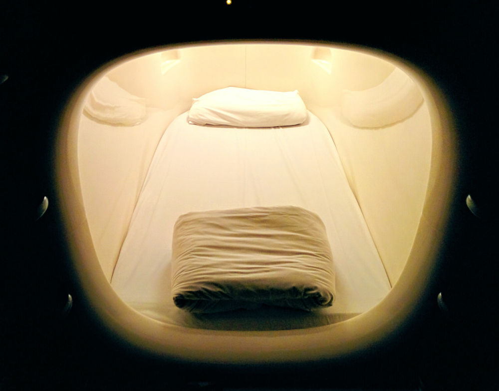 The inside of a sleeping pod with a pillow and a cover.