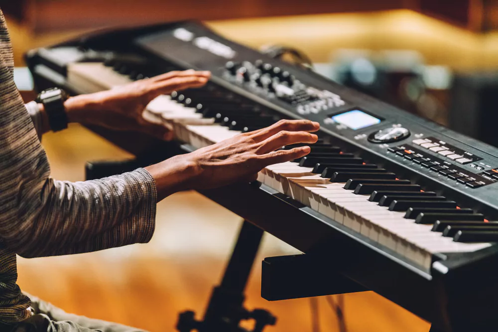 man playing electronic musical keyboard synthesizer by hands