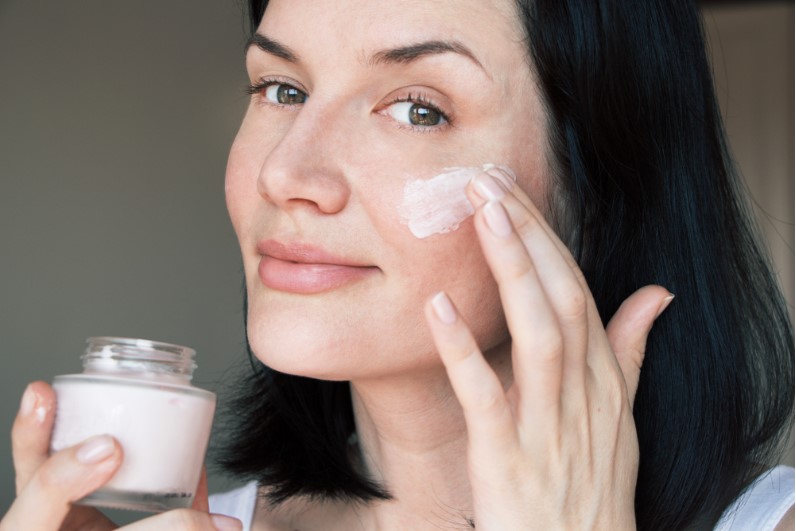 a woman applying skin lightening cream