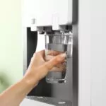 hand of a woman filling a glass of water from water purifier