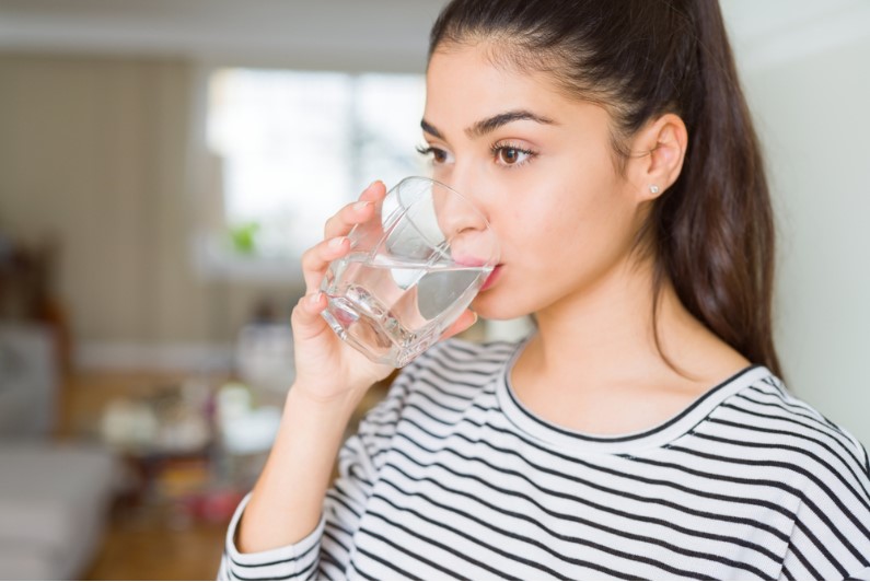 a young girl drinking a glass of water