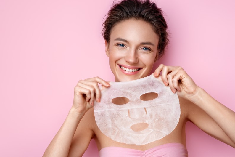 a young girl holding a face sheet mask