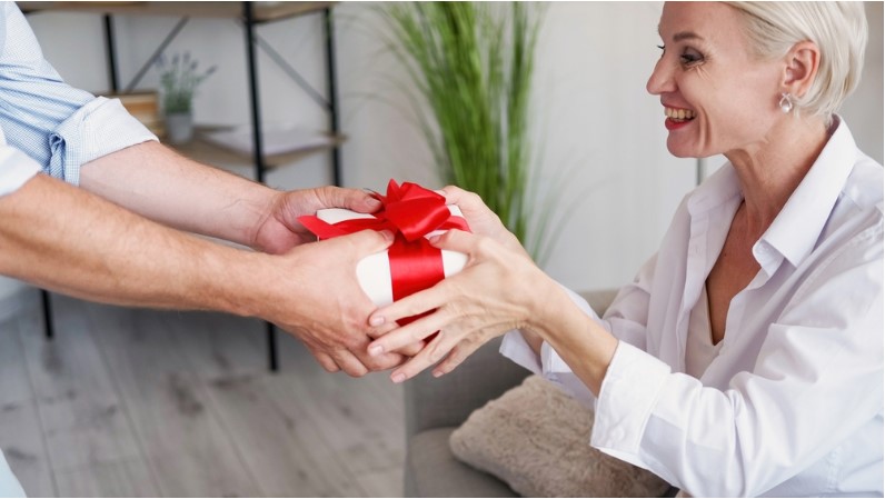 cheerful middle aged wife getting present box from husband