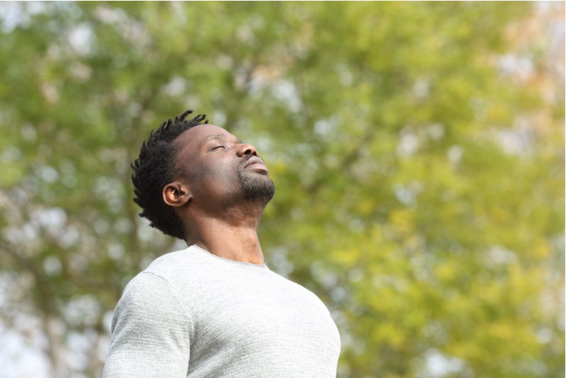 man breathing deeply fresh air in a park