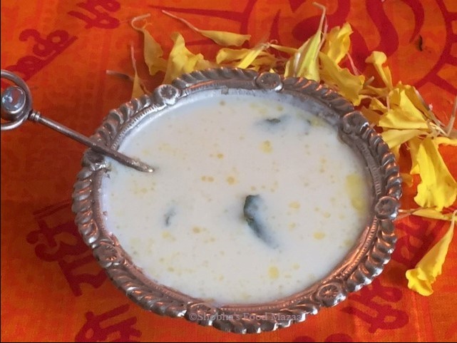 panchamrit in a steel vessel placed upon an orange coloured cloth and flowers