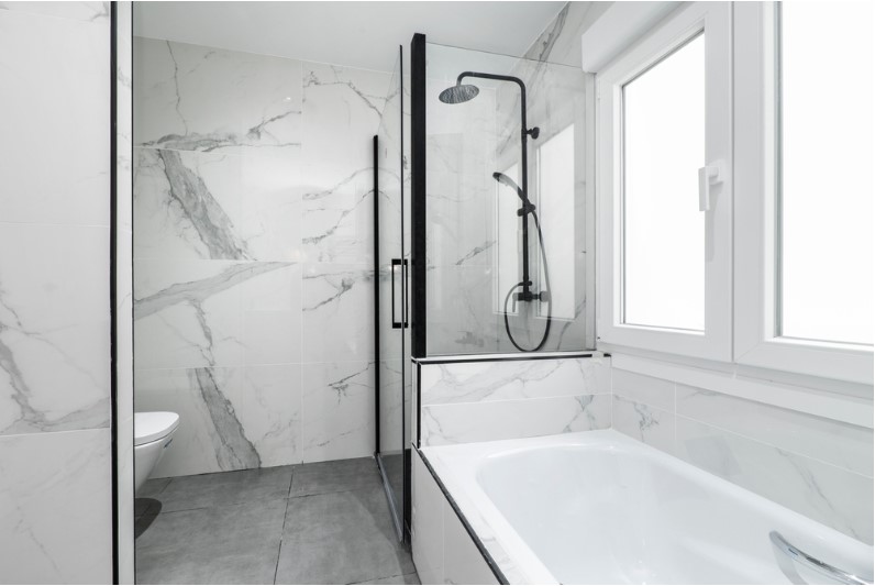 clean shower cabin with black accessories and marble tiling on the walls