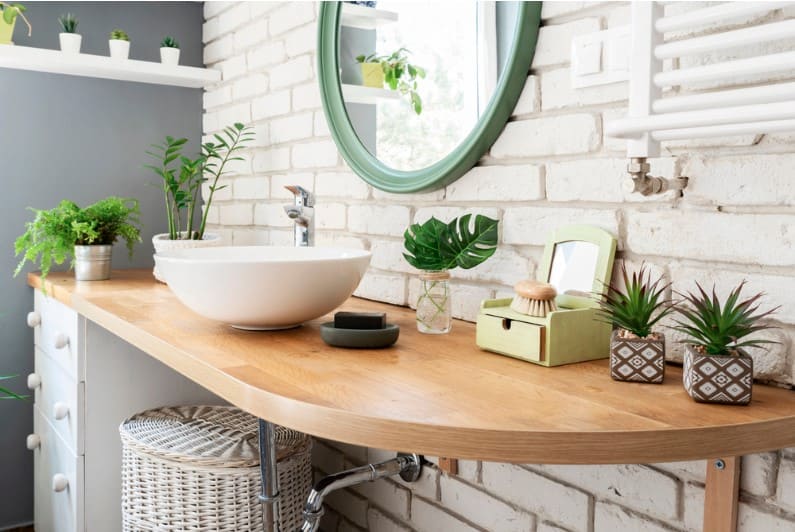 white modern bathroom with modern interior along with green plants on wooden counter and bathroom sink