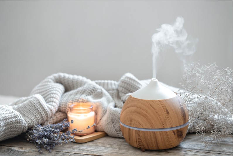 aroma composition with a modern aroma oil diffuser on a wooden surface with a knitted element candle and lavender
