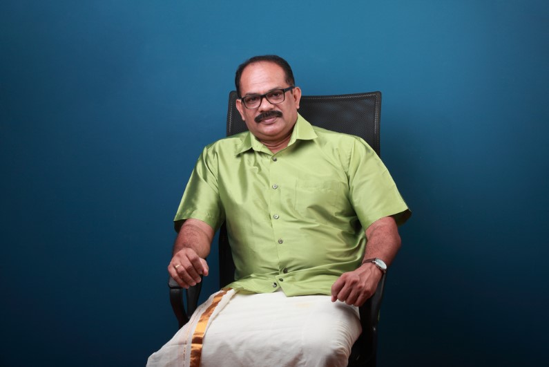 a happy middle-aged man wearing kerala style dhoti sitting on a chair