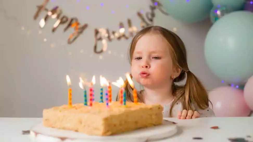 a tiny cute birthday girl blowing candles of her birthday cake