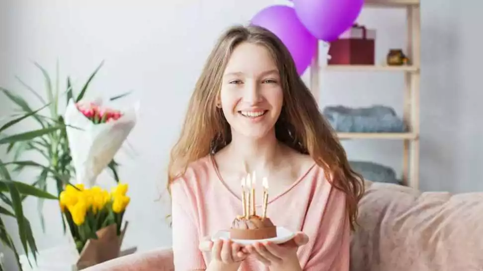 a young teen girl holding a plate with birthday cake with candles