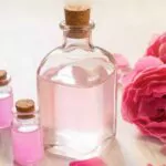 a bottle of rose water surrounded by rose petals
