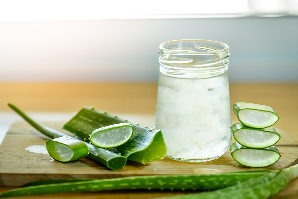 fresh aloe vera leaves and glass of aloe vera juice on wooden background