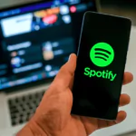 close up view of hand with smartphone and spotify ​logo on display