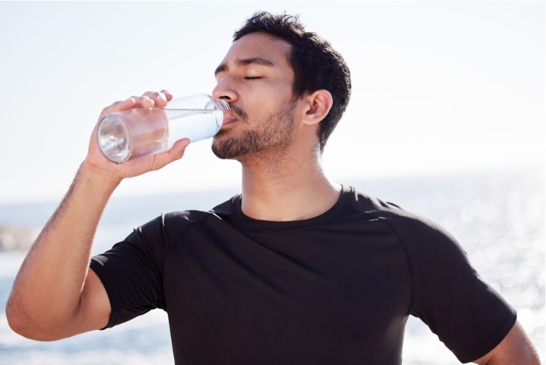 a man drinking a glass of water to stay hydrated
