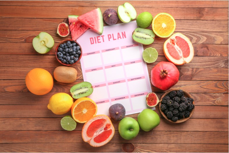 different healthy food with diet plan on wooden table