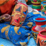 female Indian artist painting colorful terracotta pots works of handicraft for sale during handicraft fair in kolkata