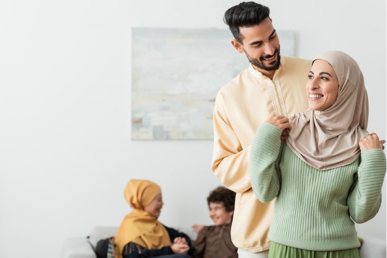 happy arabian man embracing muslim wife near blurred multiethnic family