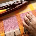 a woman touching a handloom fabric on the loom
