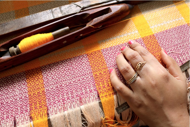a woman touching a handloom fabric on the loom