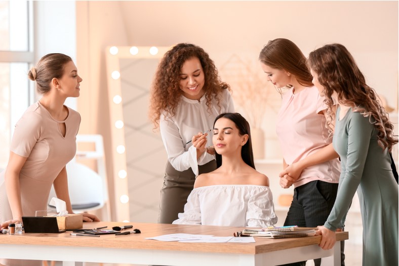 young woman teaching students in makeup school
