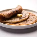 sweet puran poli served on a plate with pure ghee over colourful or wooden background