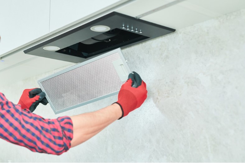 a man removing a filter from cooker hood for cleaning or service