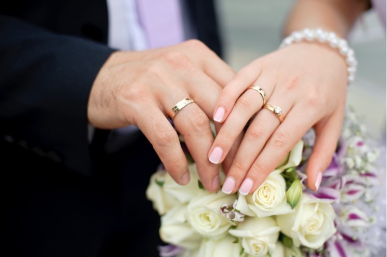 couple hands with rings on a bouquet