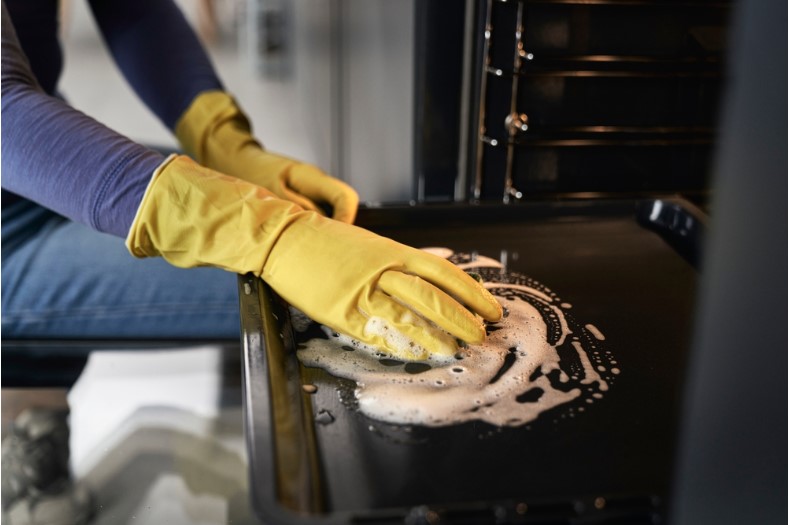 close up of woman cleaning and scrubbing oven at home