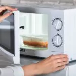 a woman preparing food with a microwave oven