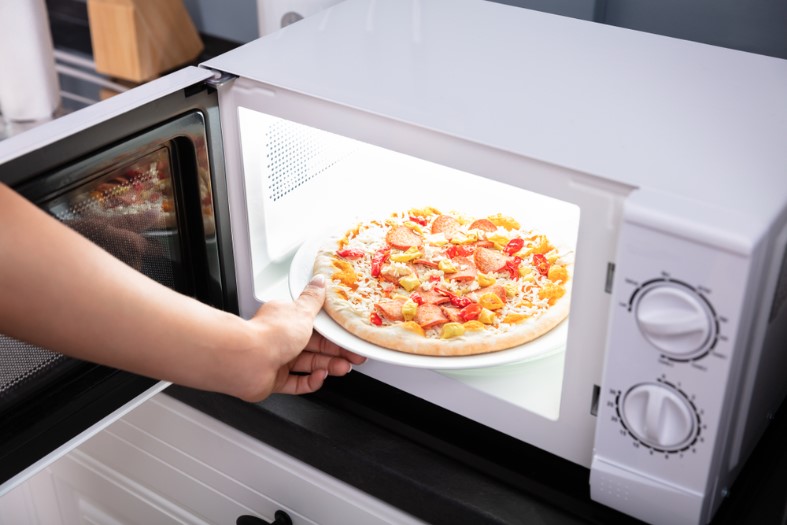 close-up of a woman baking pizza in a microwave oven