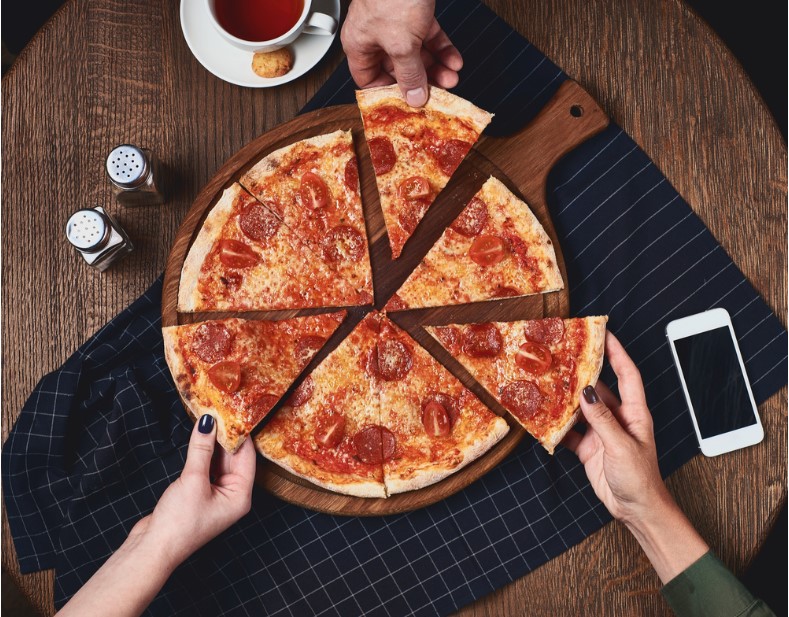 people taking slices of pepperoni pizza from wooden board