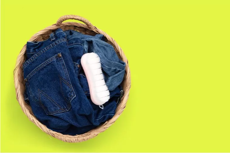 jeans in laundry basket on green background